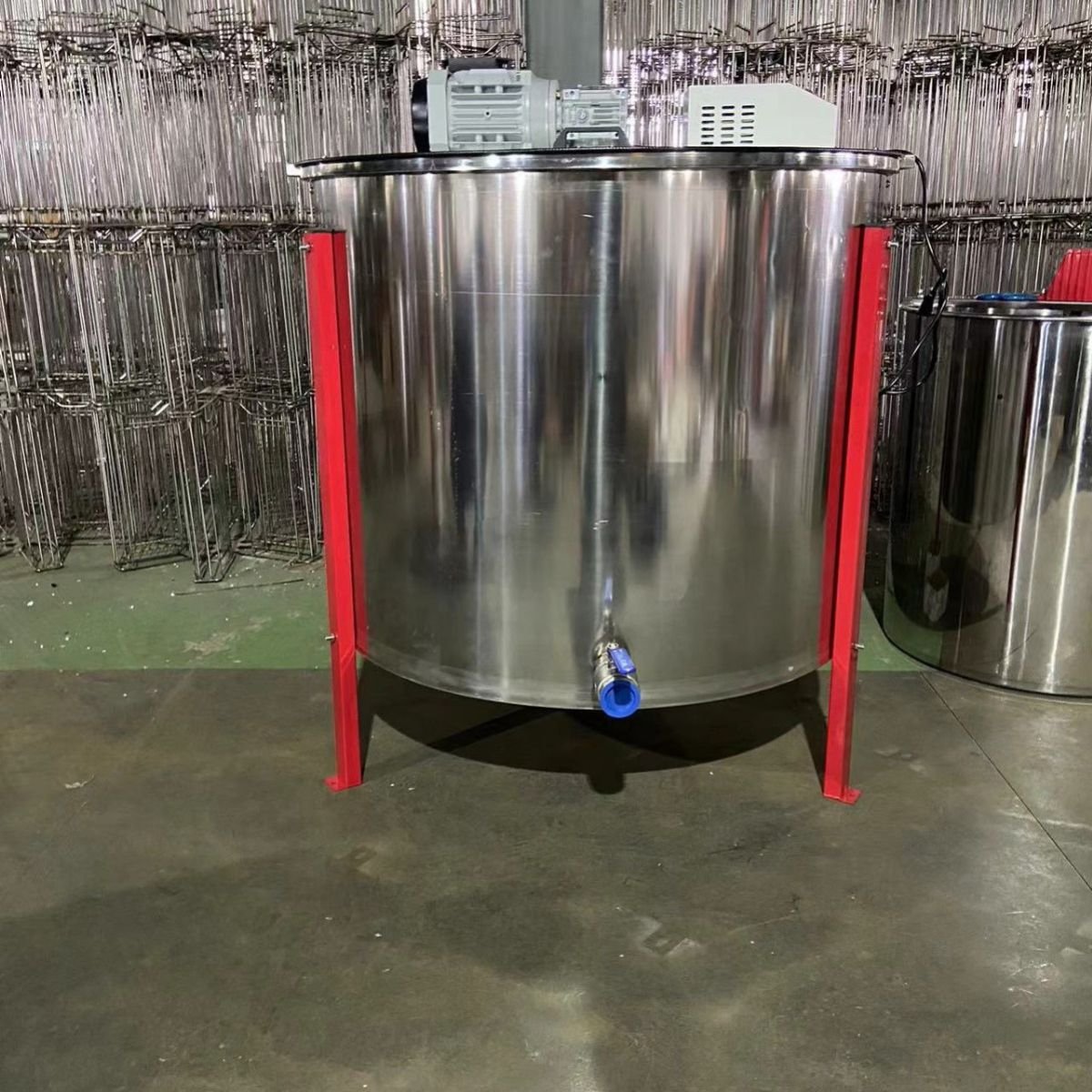 Front view of 24-frame electric honey extractor, 304 stainless tank with red legs and blue ball valve